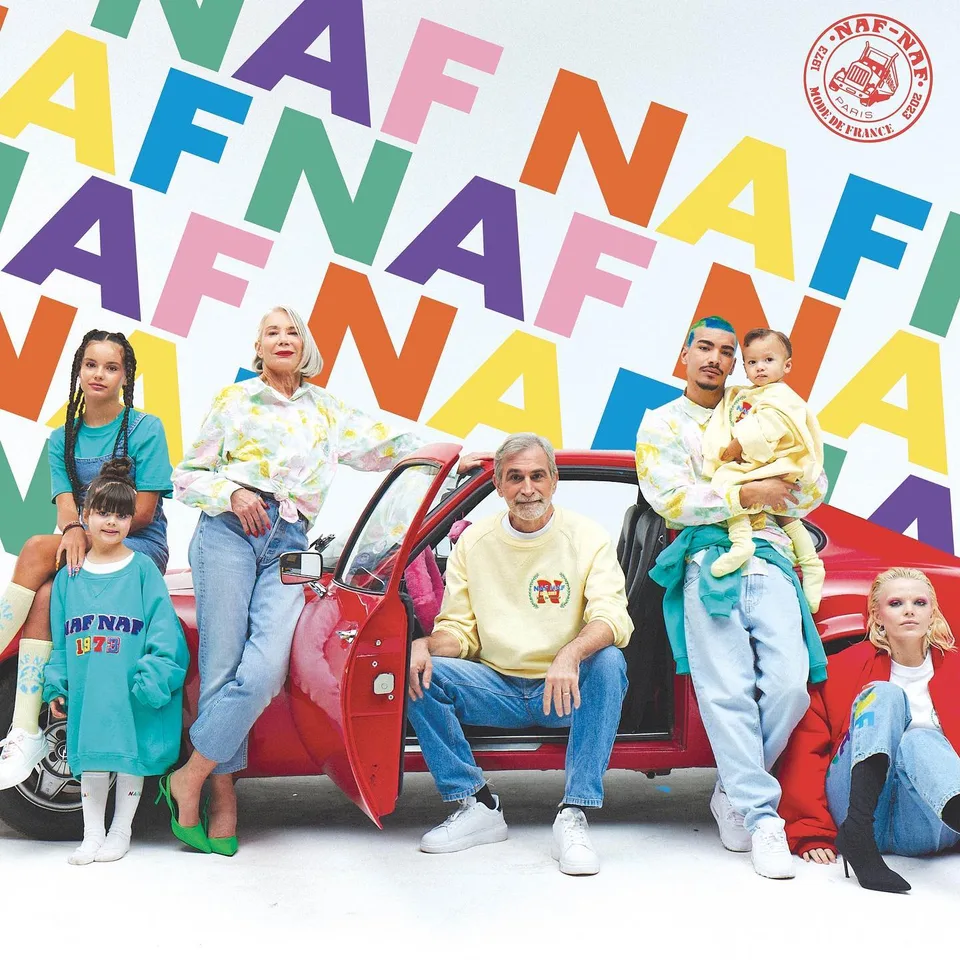 Campagne Naf Naf : famille de mannequins autour d'une voiture rouge, lettres NAF NAF colorées en fond