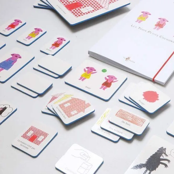 Cartes illustrées et livre des Trois Petits Cochons étalés sur une table
